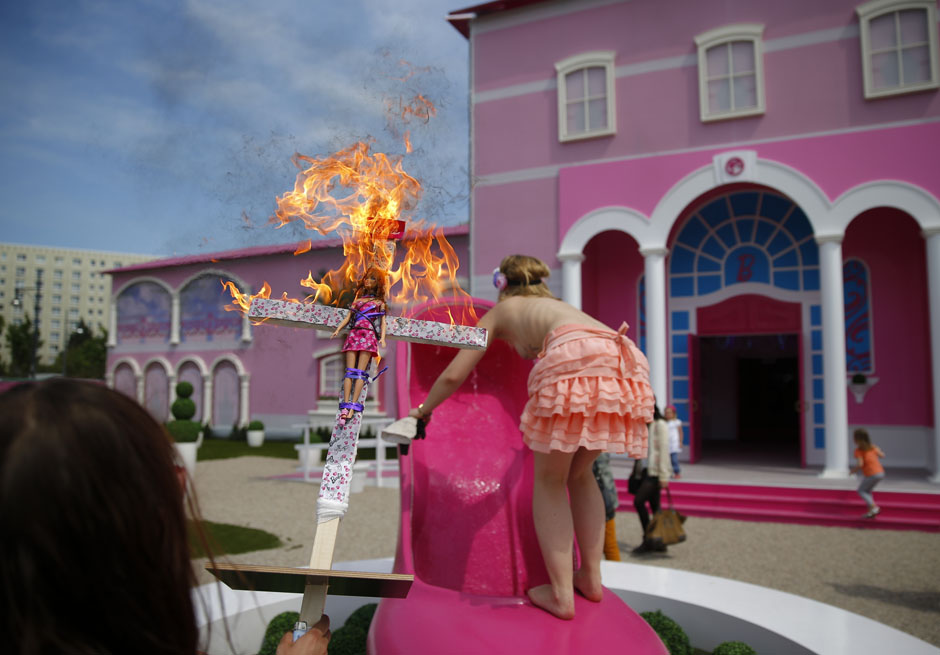 Activists from women's rights group Femen burn a barbie doll on a cross as they protest outside a "Barbie Dreamhouse" of Mattel's Barbie dolls in Berlin